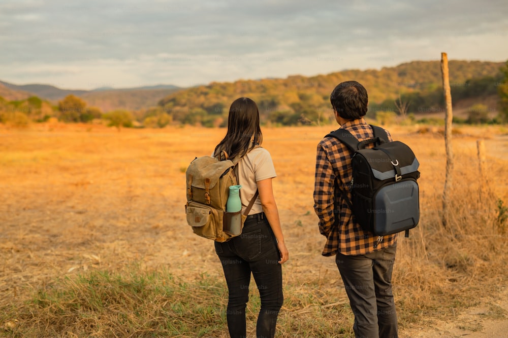 a man and a woman with backpacks standing in a field
