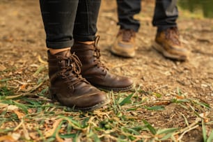 a pair of brown boots standing on top of a grass covered field