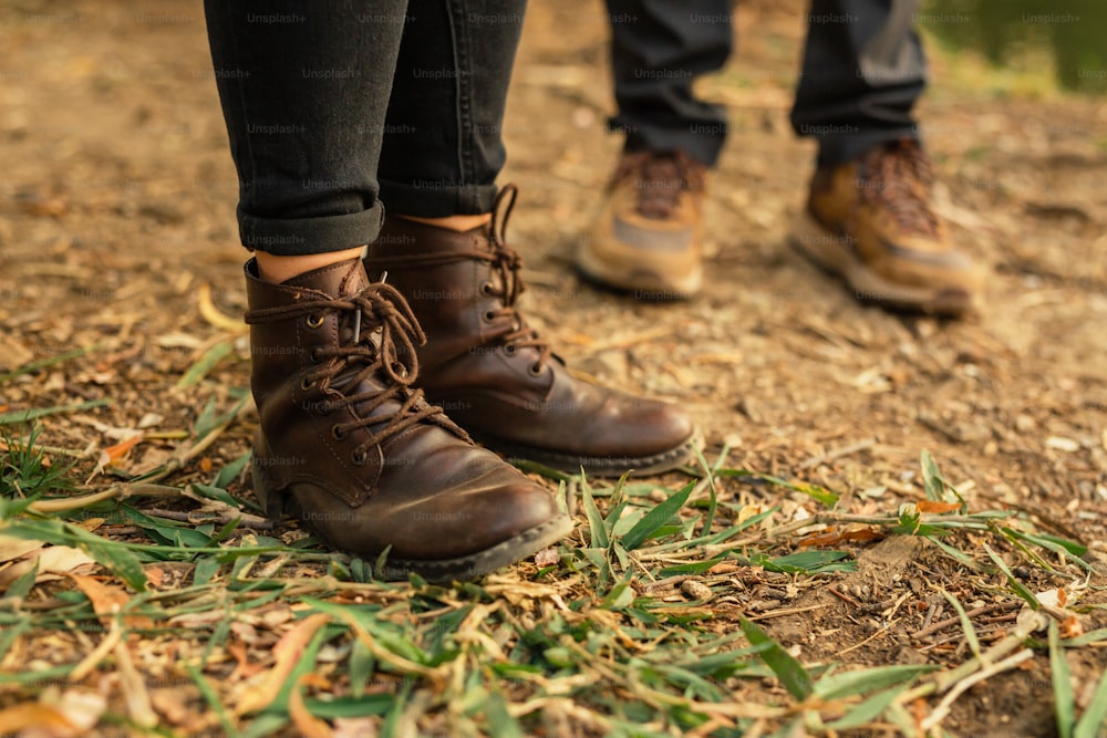 a pair of brown boots standing on top of a grass covered field