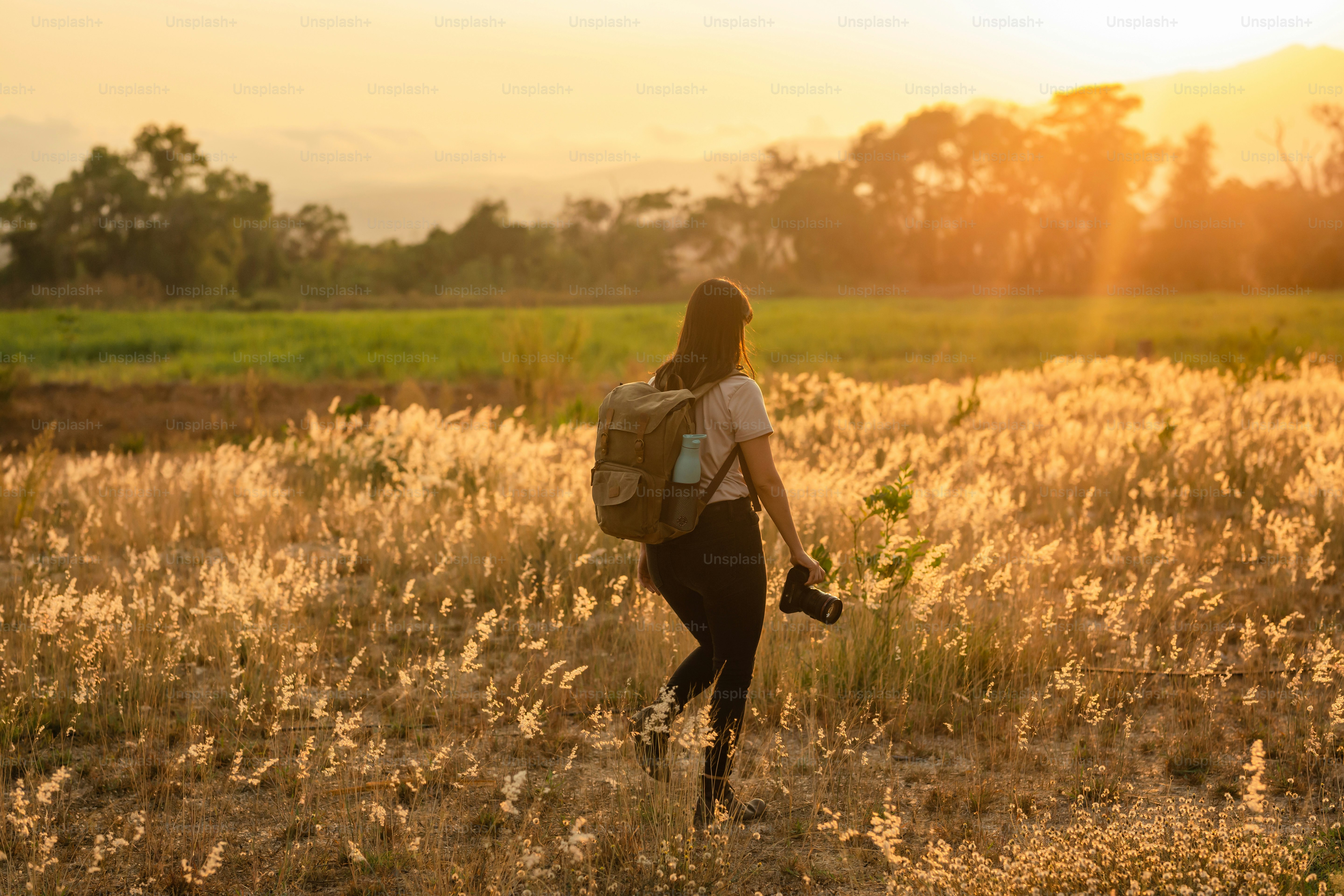a woman with a backpack walking through a field