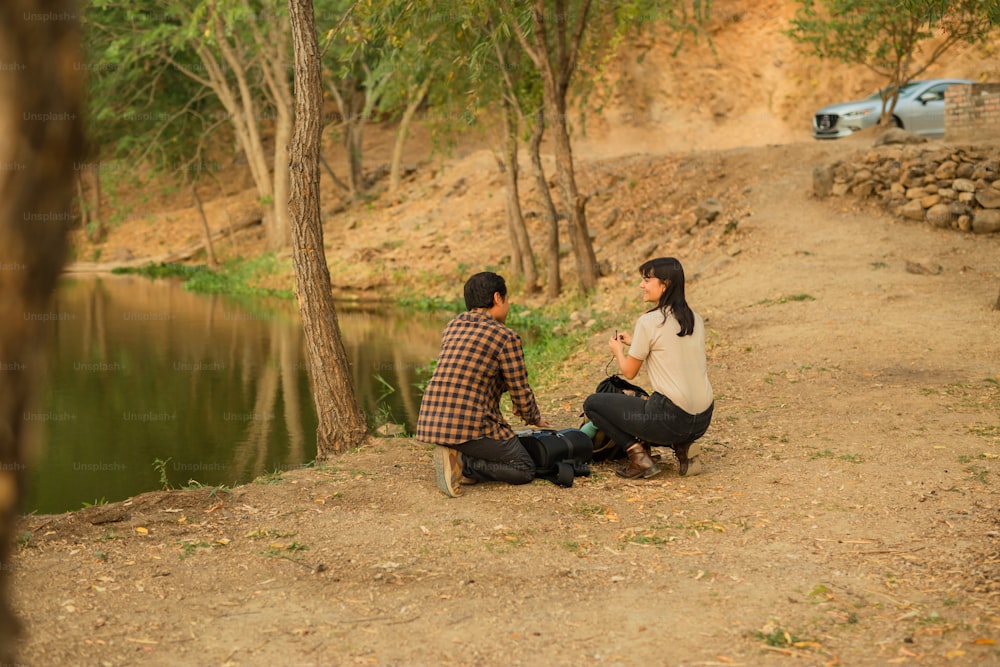 a man and a woman sitting on a bench next to a river
