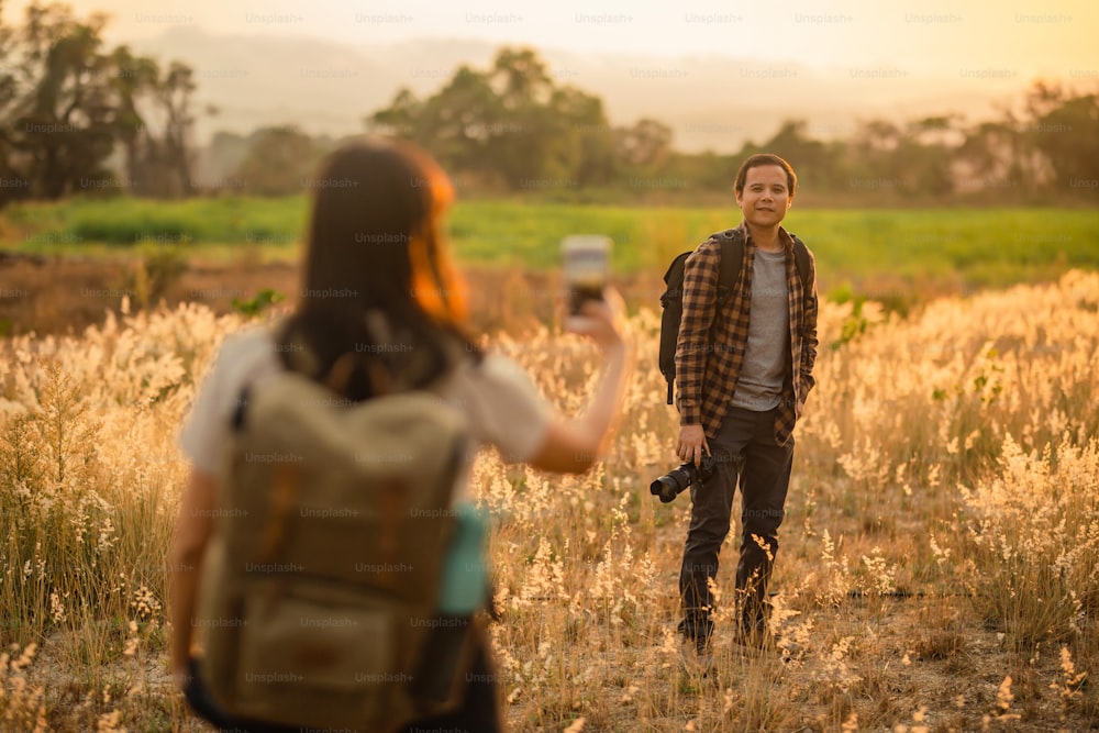a man taking a picture of a woman in a field