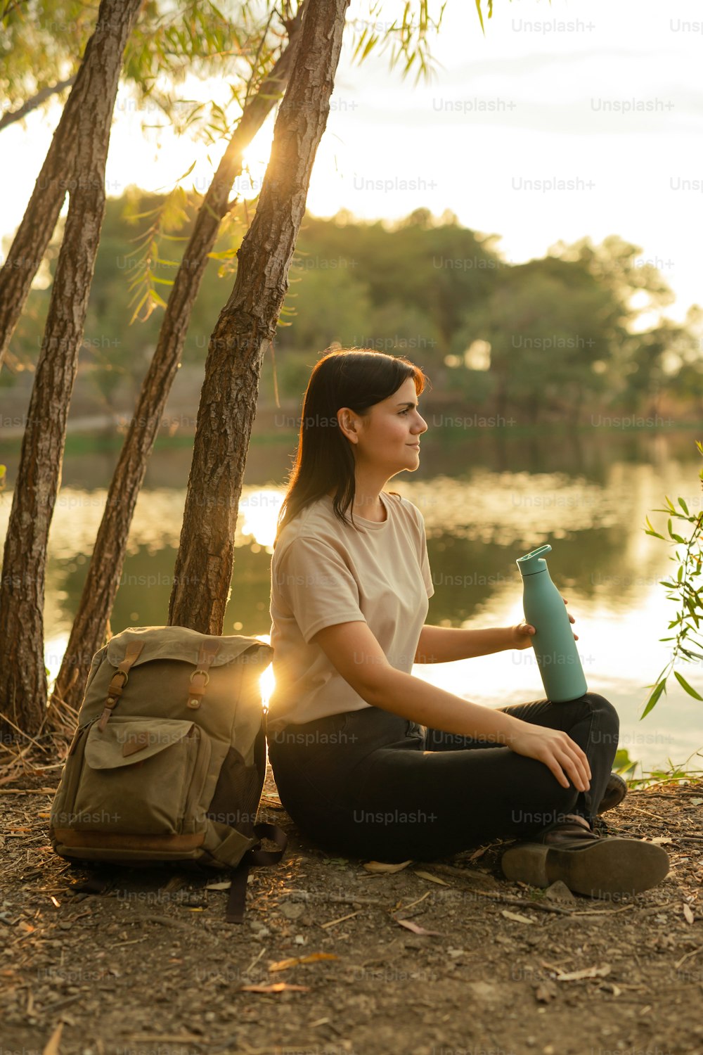 a woman sitting on the ground with a backpack and a water bottle