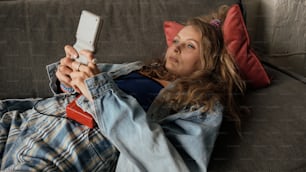 a woman laying on a couch holding a cell phone