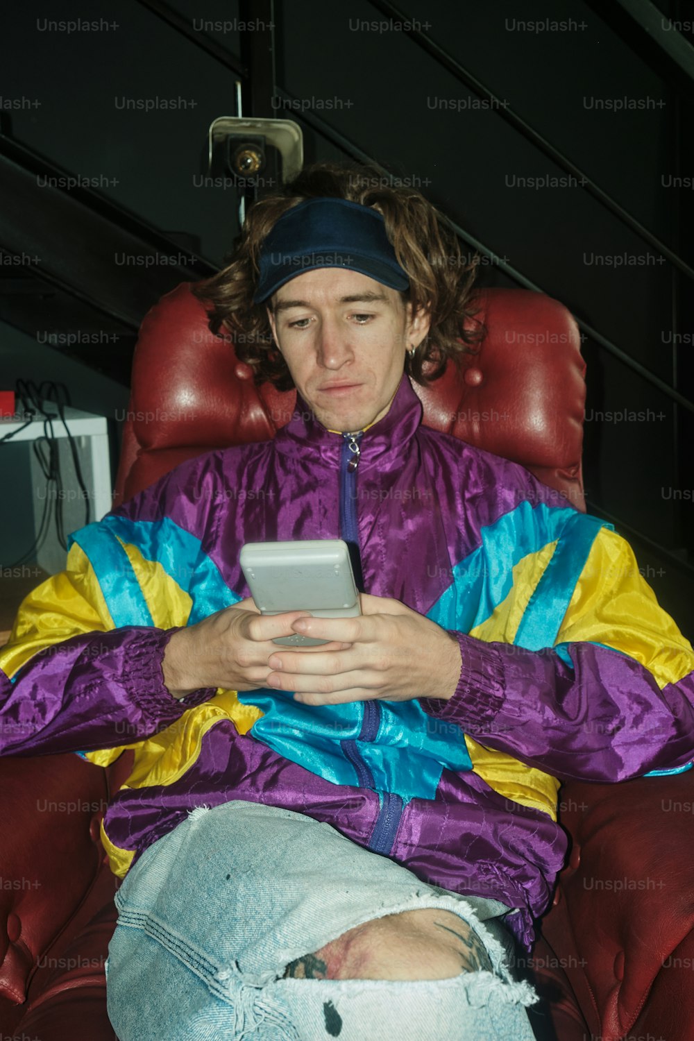 um homem sentado em uma cadeira olhando para um celular