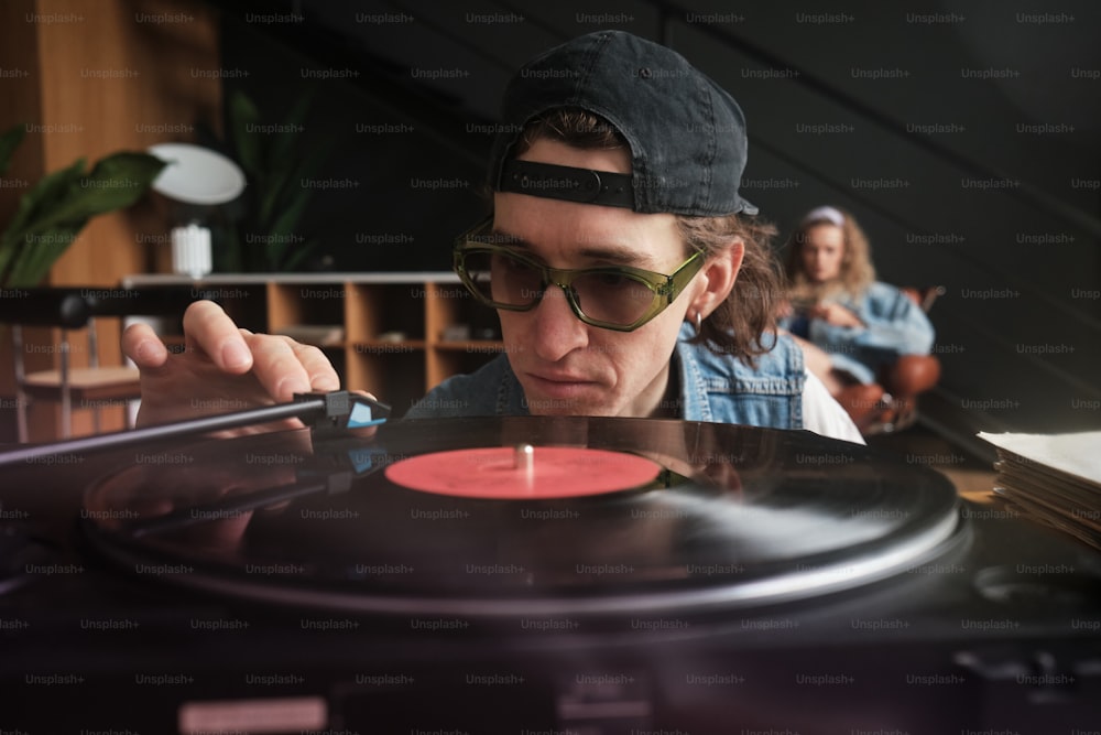 a man in a hat and sunglasses playing a record