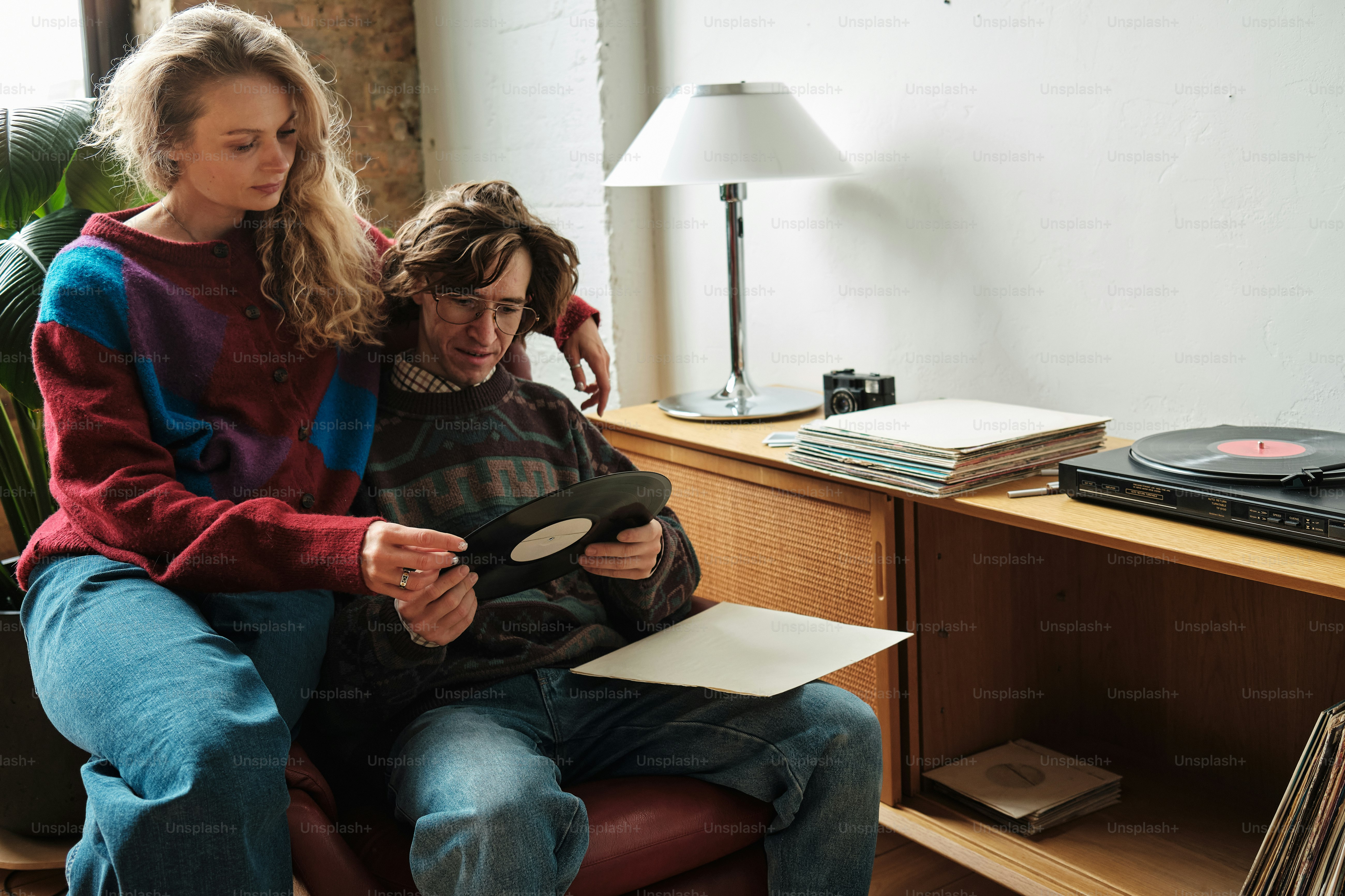 a man and a woman sitting on a couch looking at a tablet