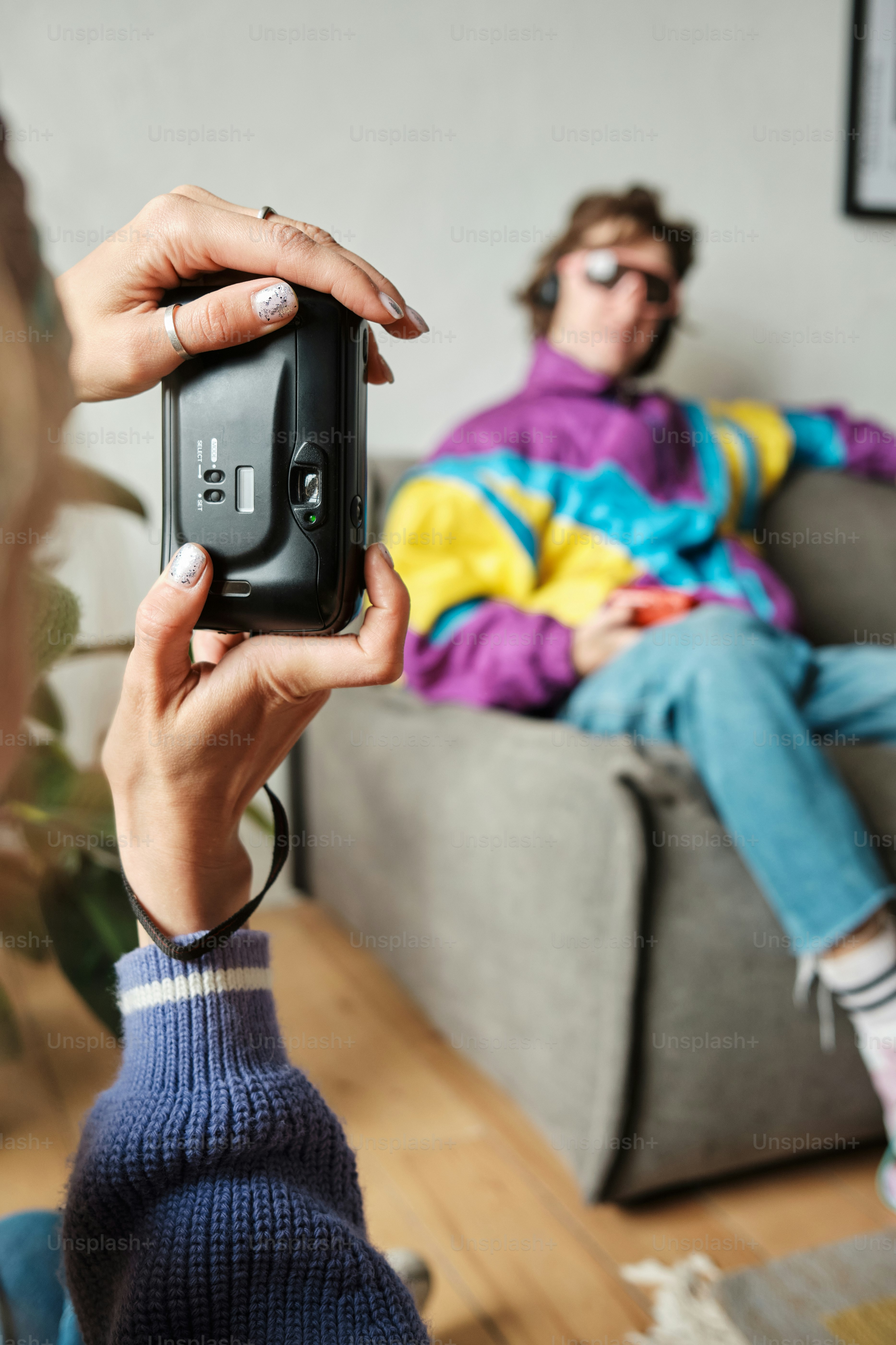 a woman taking a picture of a man sitting on a couch