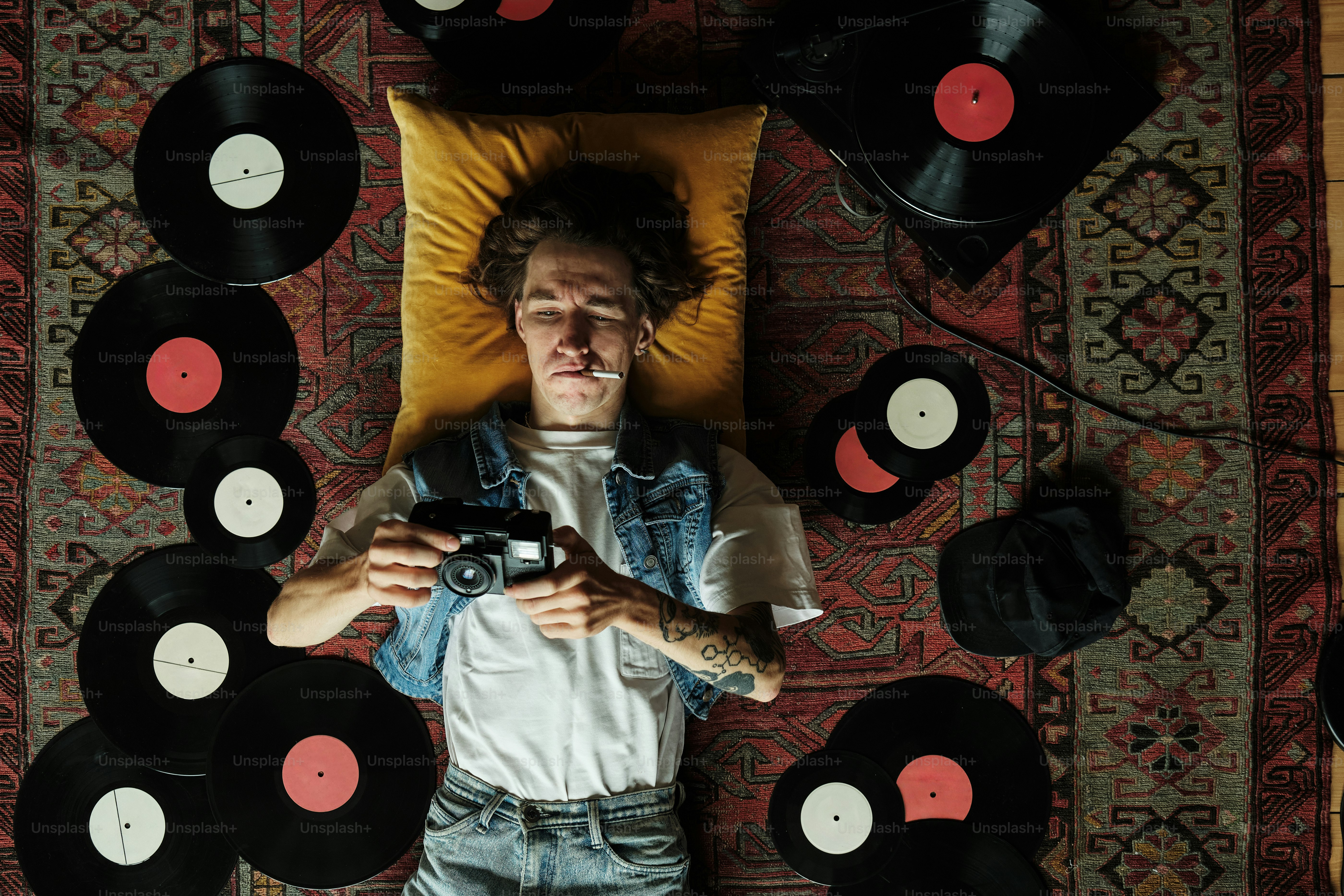 a man laying on top of a bed surrounded by records