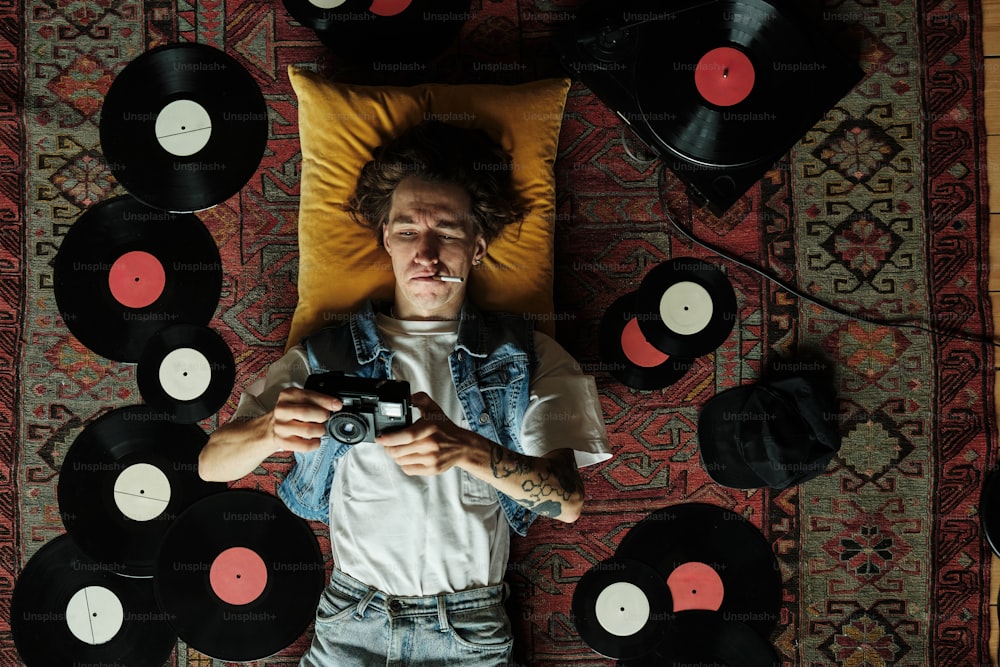 a man laying on top of a bed surrounded by records
