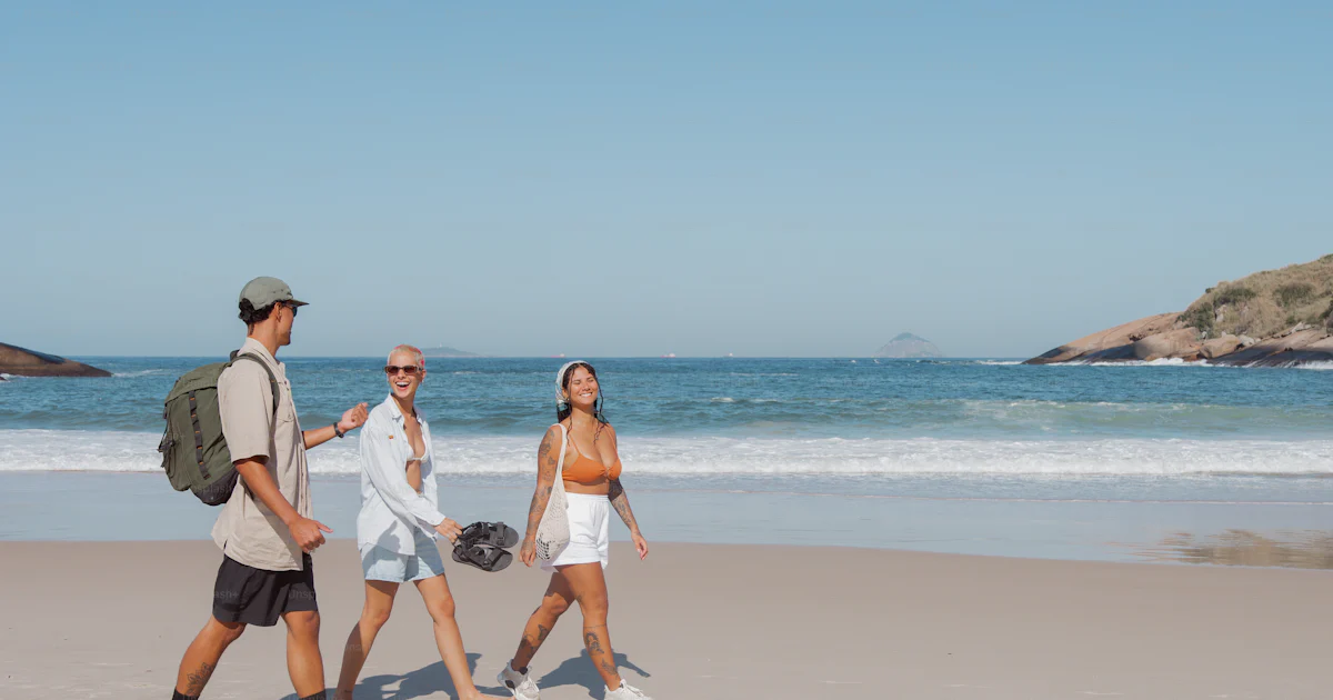 A man and two women walking on the beach photo – Adventure Image on ...