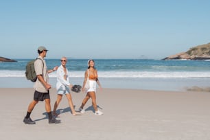 Un hombre y dos mujeres caminando por la playa