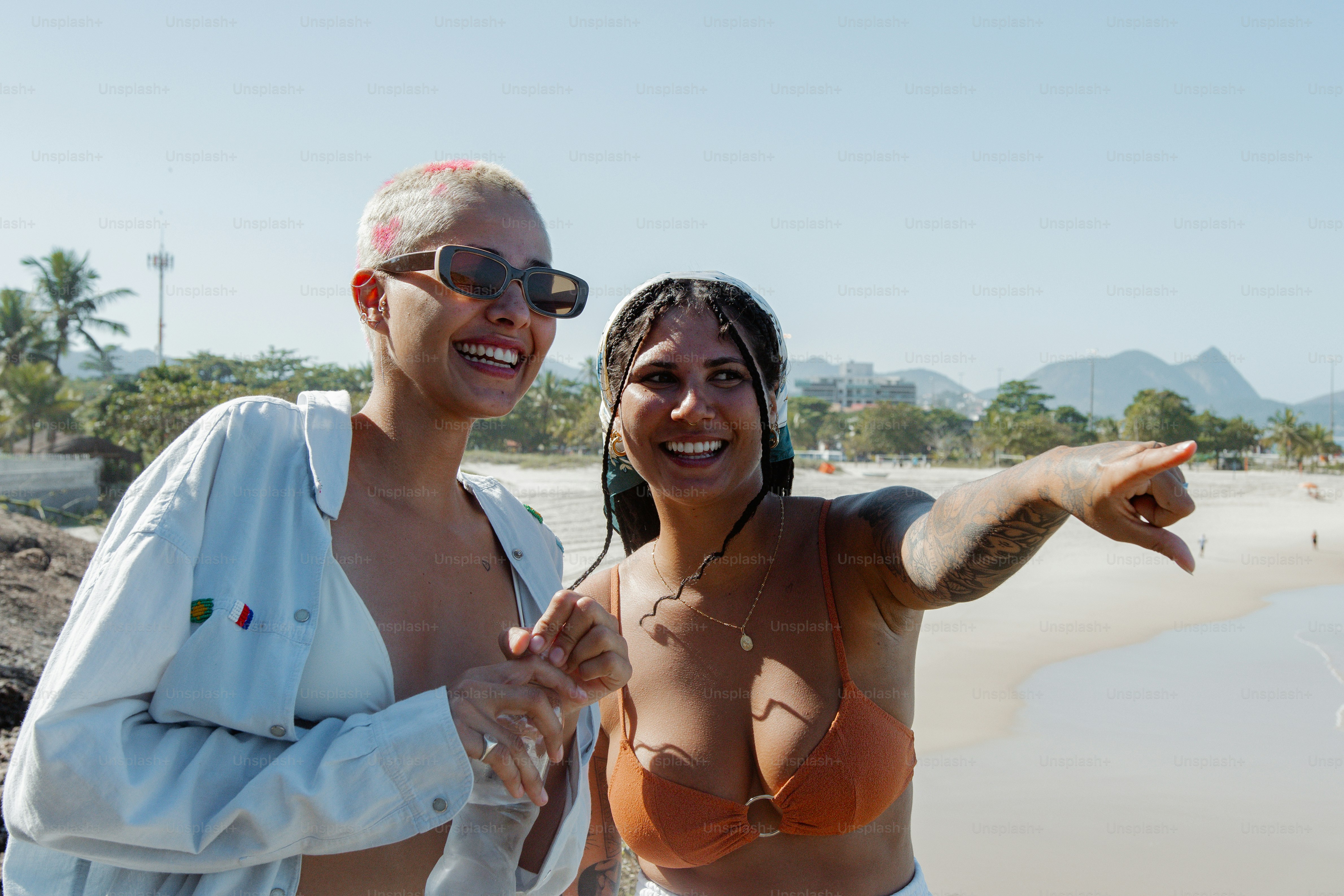 Un par de mujeres de pie una al lado de la otra en una playa