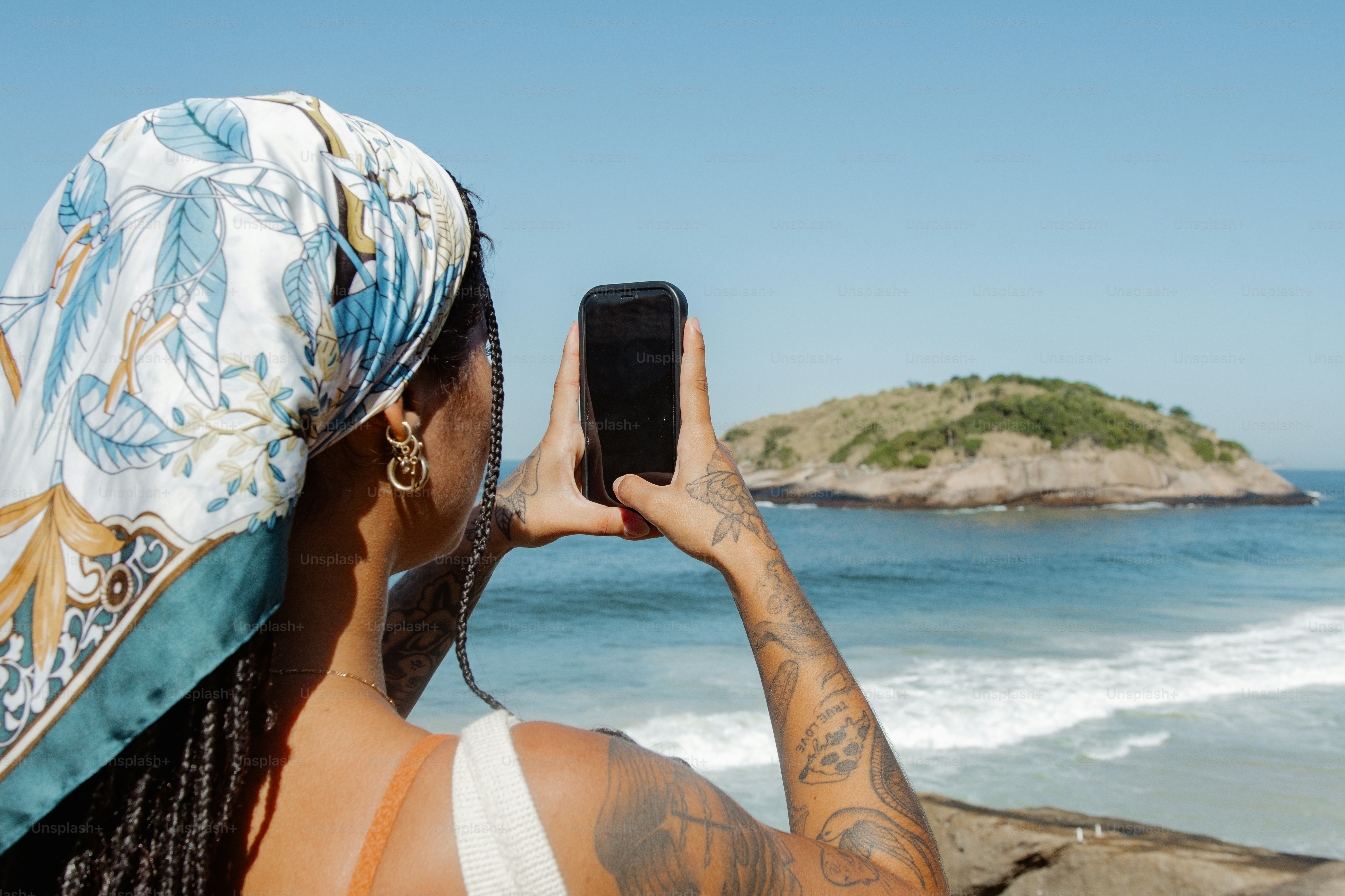 eine frau, die mit ihrem handy ein foto des ozeans macht
