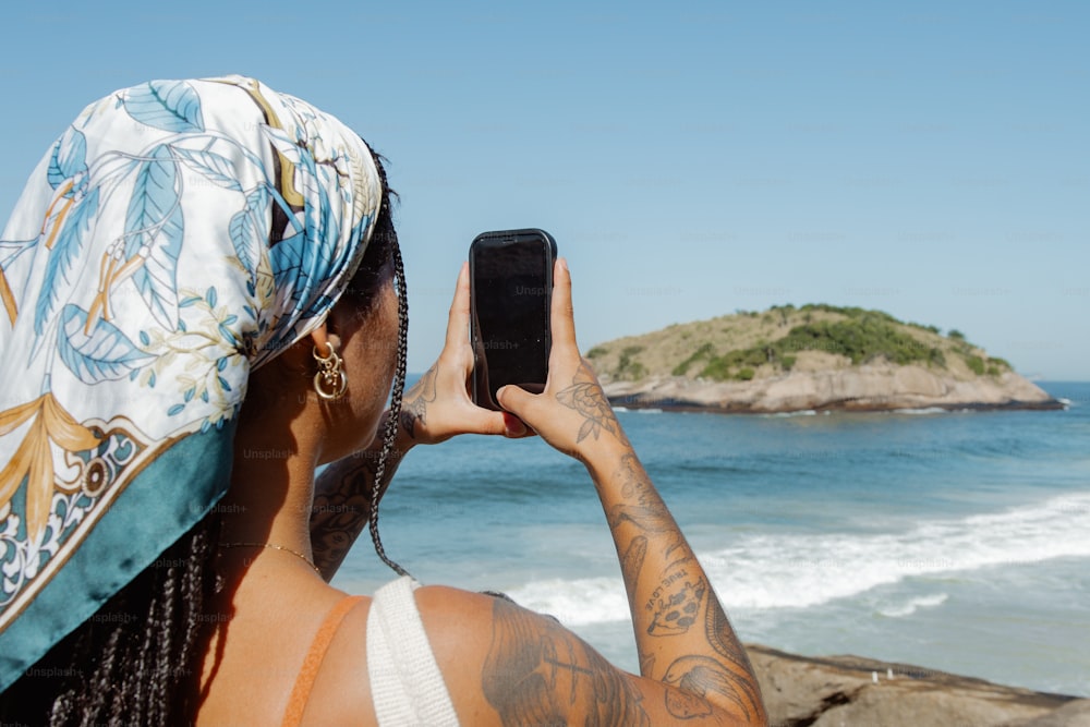 携帯電話で海の写真を撮る女性