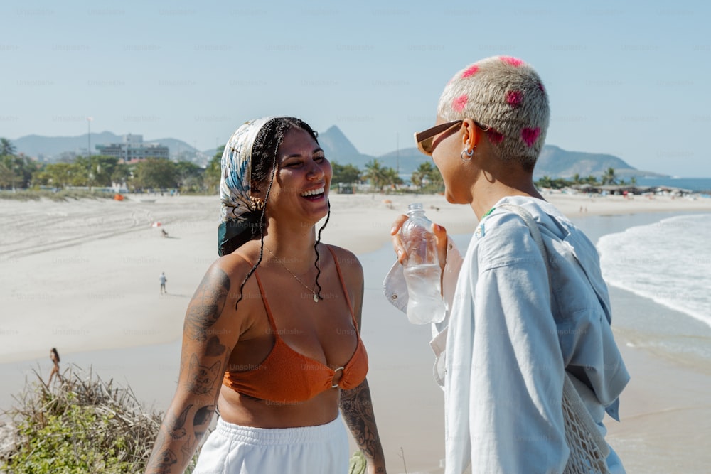 a man and a woman standing on a beach next to the ocean