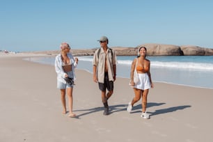 a man and two women walking on the beach