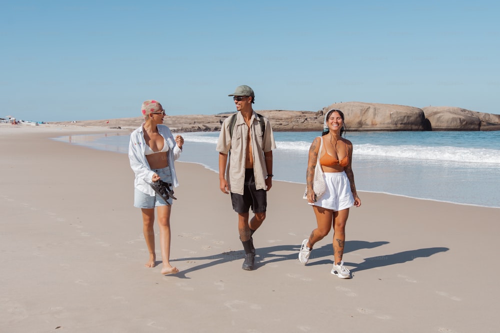 Un hombre y dos mujeres caminando por la playa