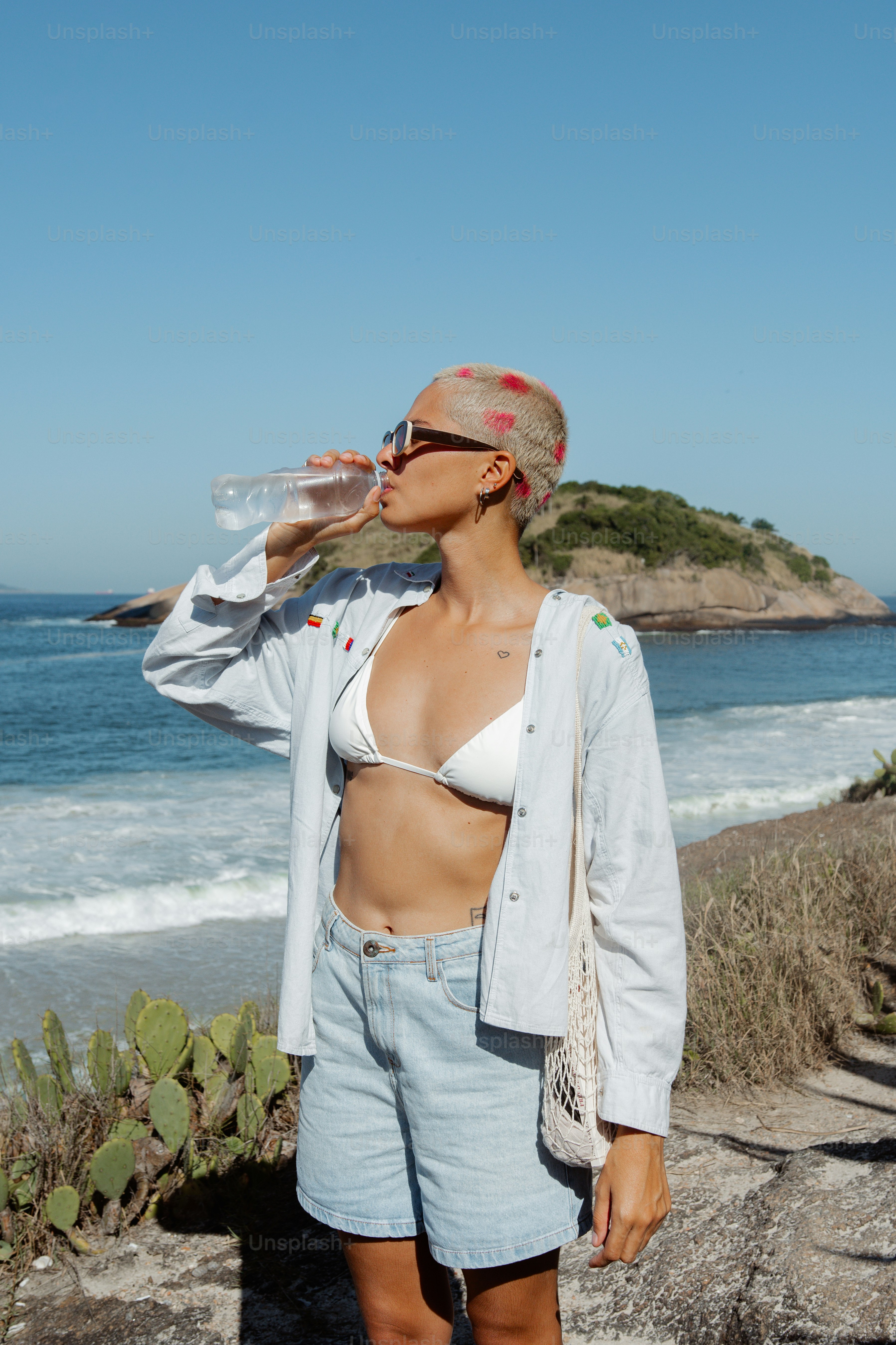 Eine Frau im Bikini trinkt Wasser aus einer Flasche