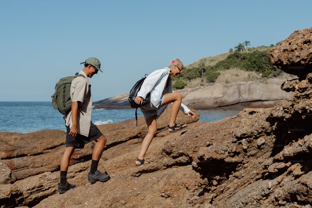 two men walking up a rocky cliff by the ocean