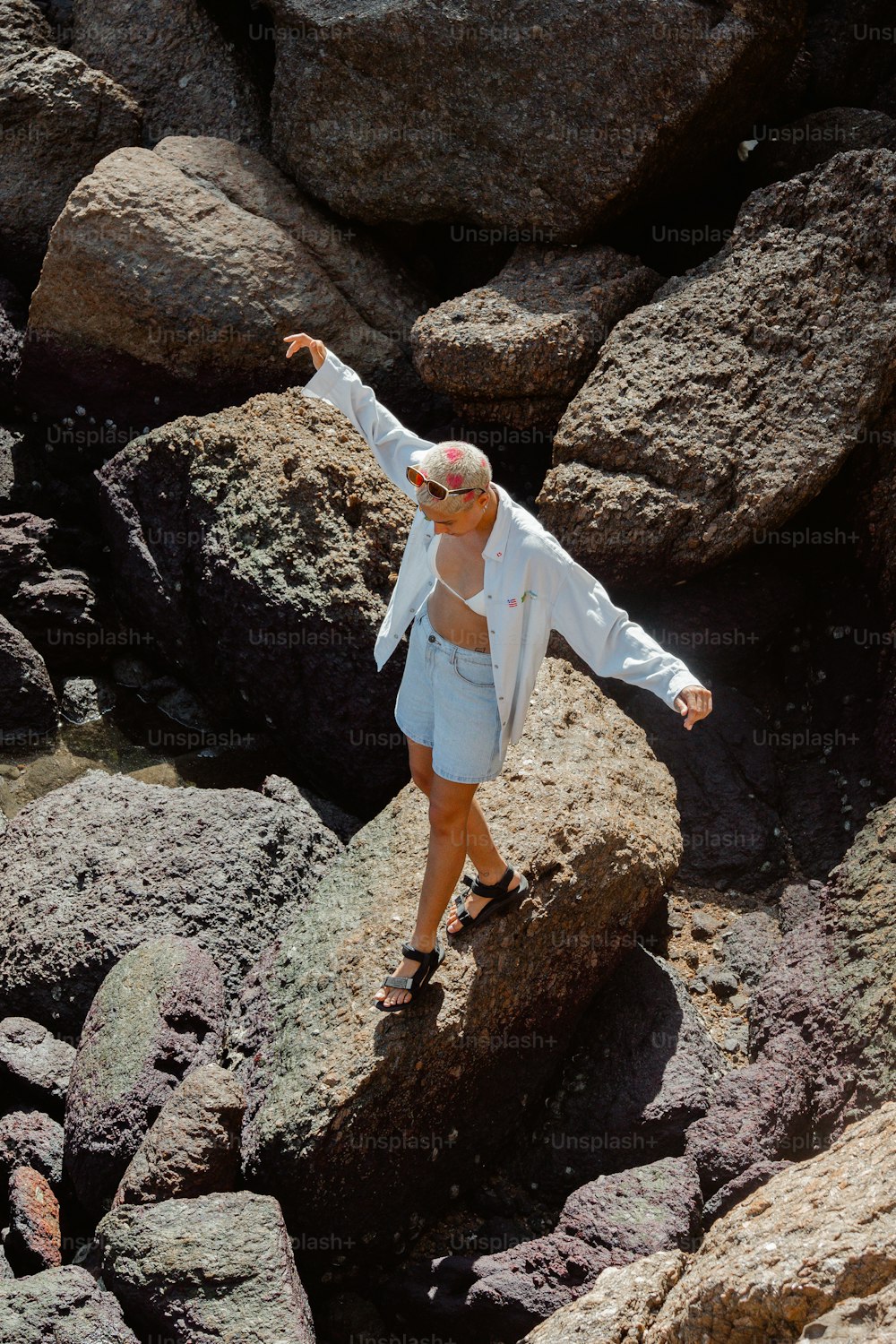 Una mujer parada sobre rocas apuntando a algo