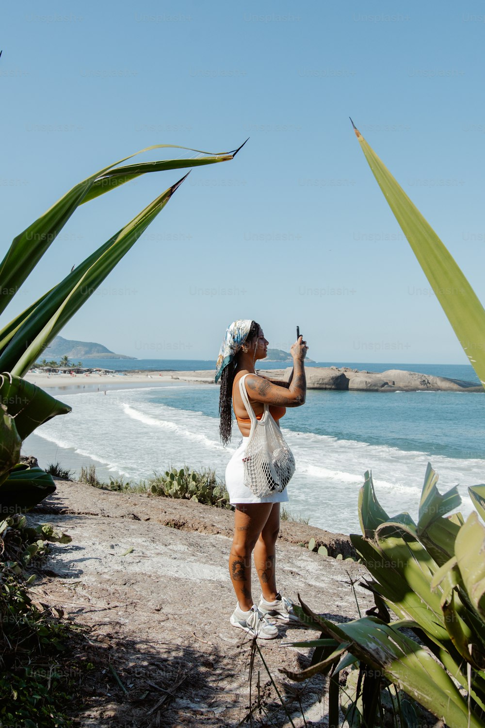 Une femme prenant une photo de l’océan avec son téléphone portable