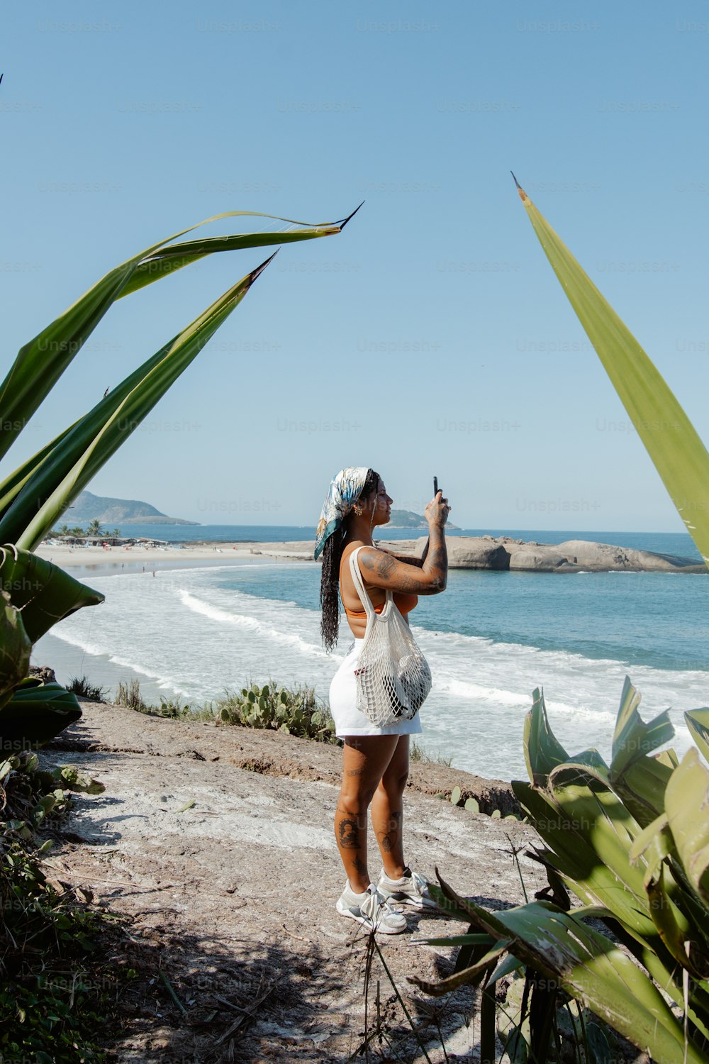 a woman taking a picture of the ocean with her cell phone