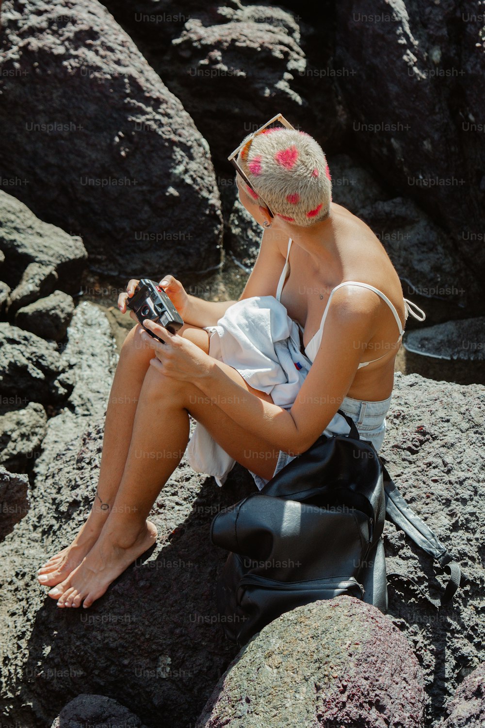 a woman sitting on a rock looking at her cell phone