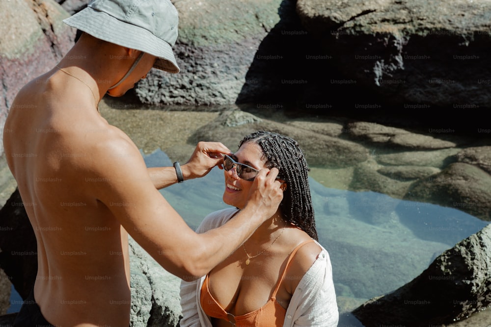 a man helping a woman put on her sunglasses