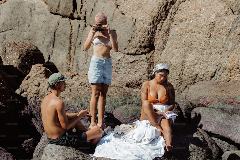 a group of people sitting on top of a rocky beach