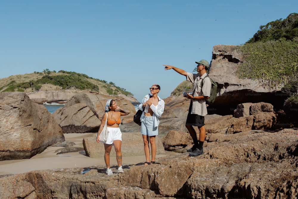 Un groupe de personnes debout au sommet d’une plage rocheuse