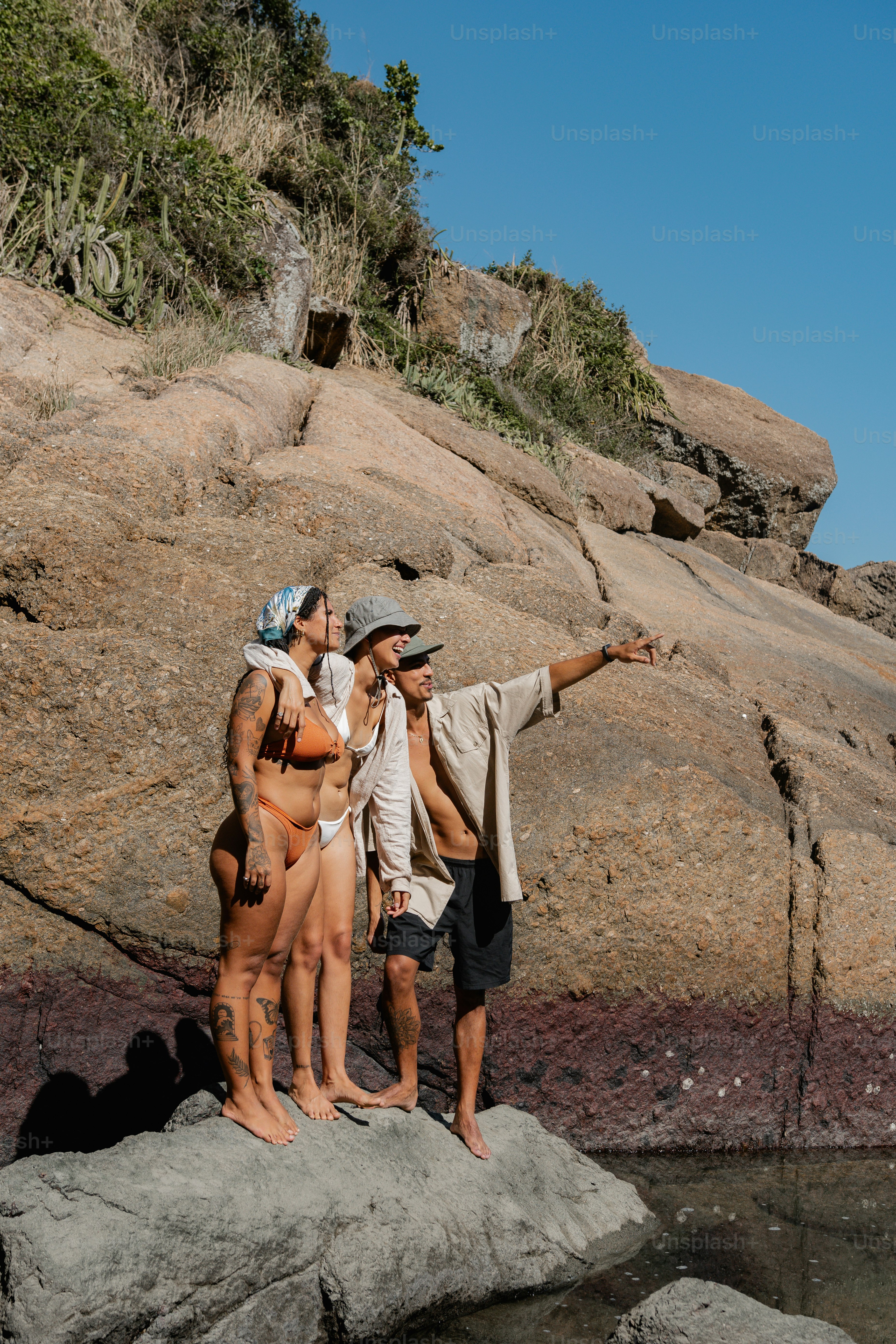 a group of men standing on top of a rock next to a body of water