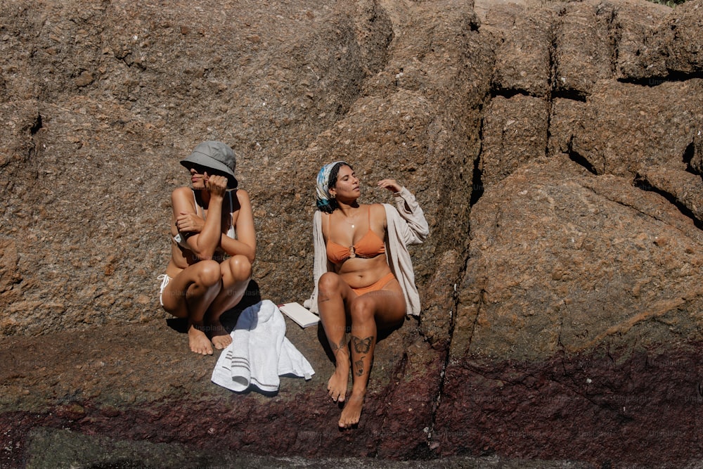 ein paar frauen, die nebeneinander an einem strand sitzen