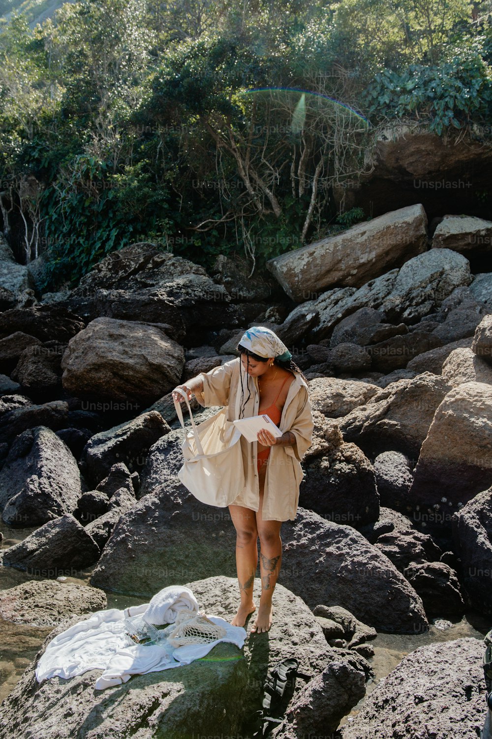 a woman standing on a rocky beach next to a body of water