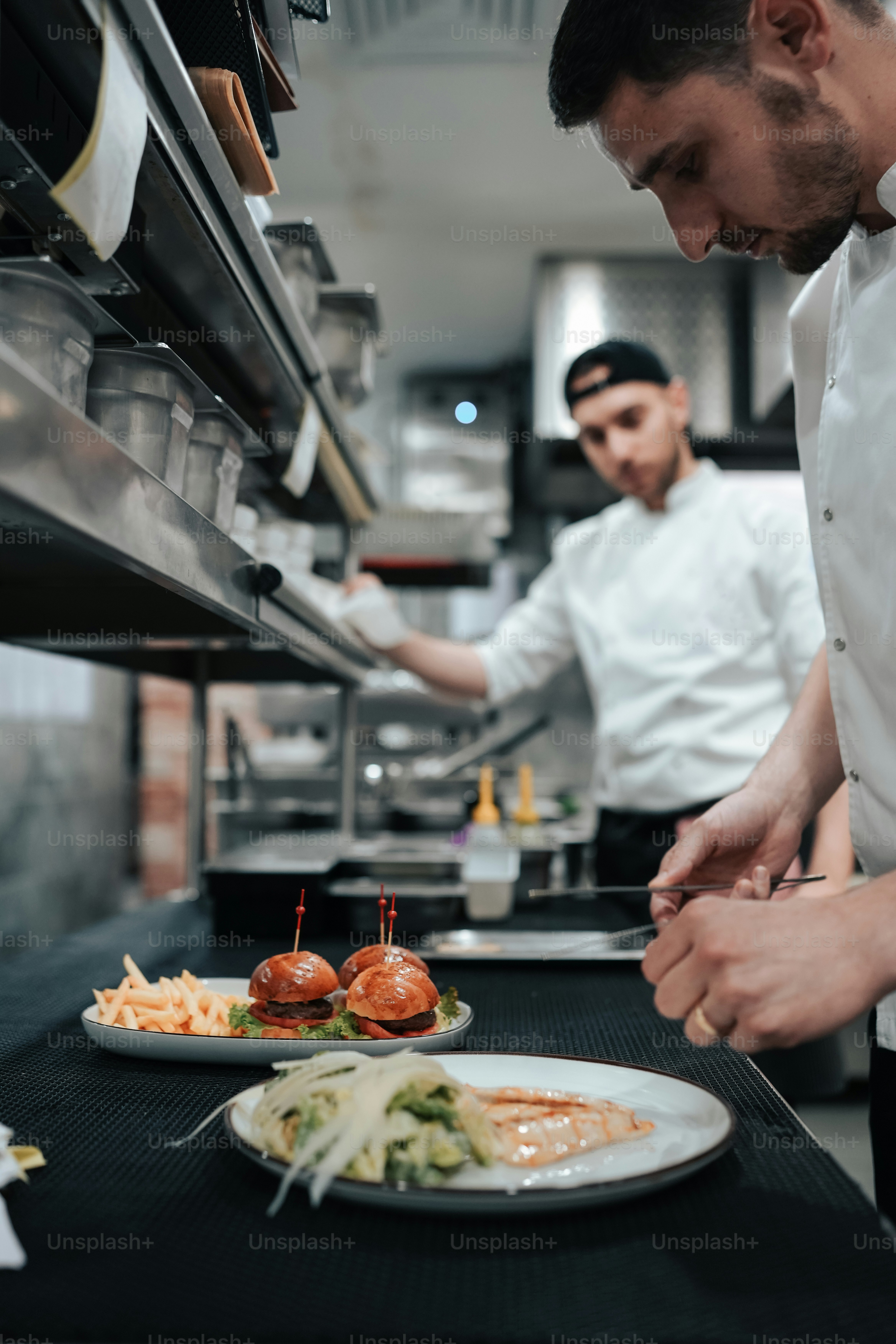 Dos hombres en una cocina preparando comida en un plato