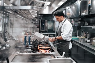a man in a kitchen preparing food on top of a stove