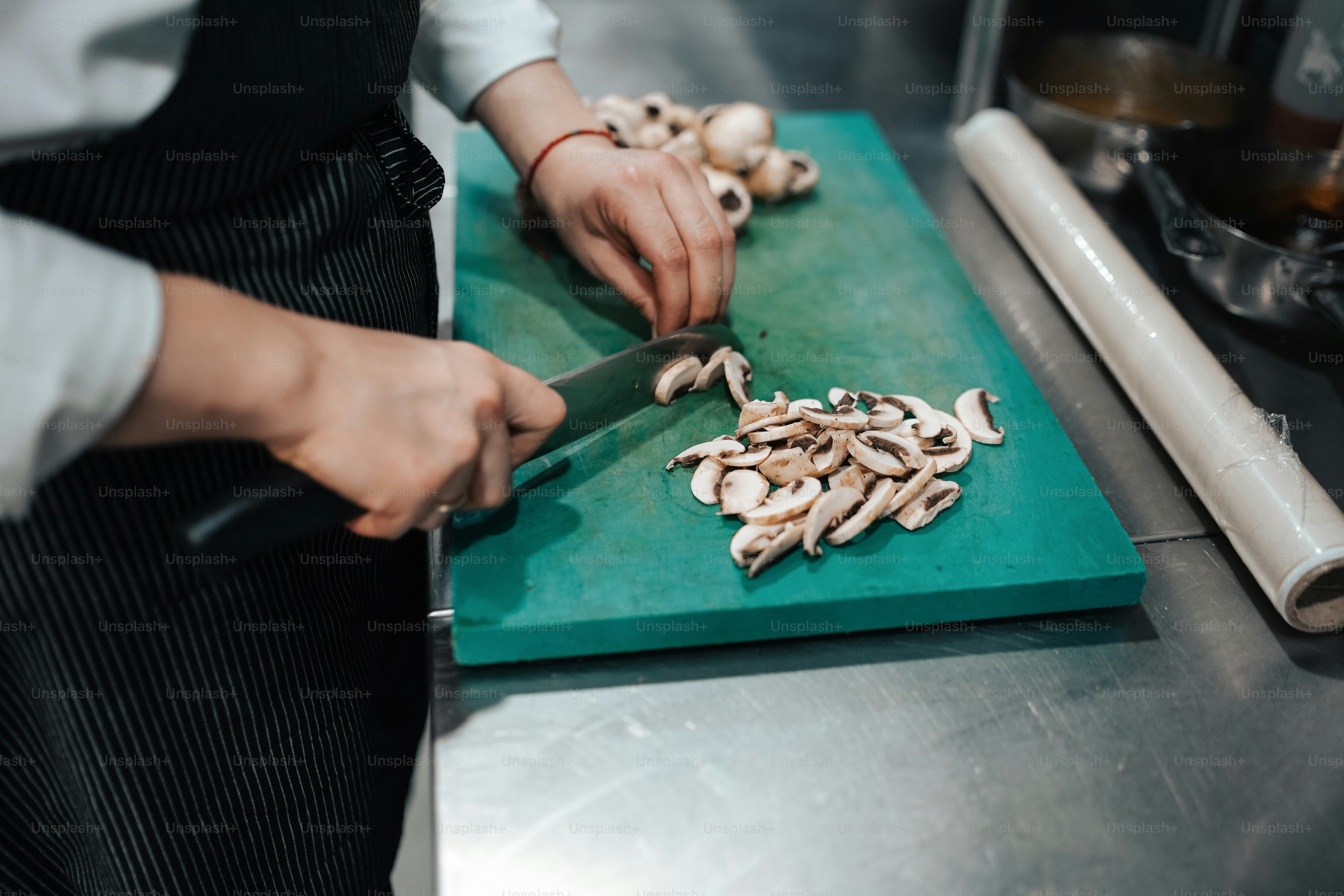 a person cutting mushrooms on a green cutting board
