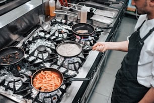 a man in a kitchen cooking food on a stove