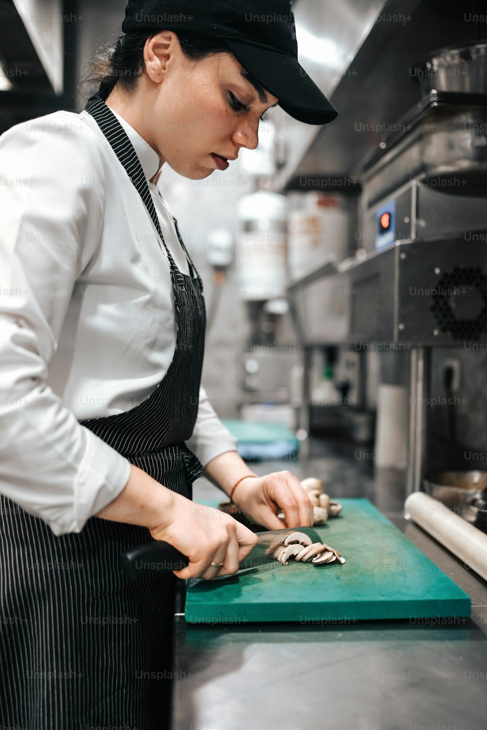 Una mujer en una cocina cortando champiñones en una tabla de cortar