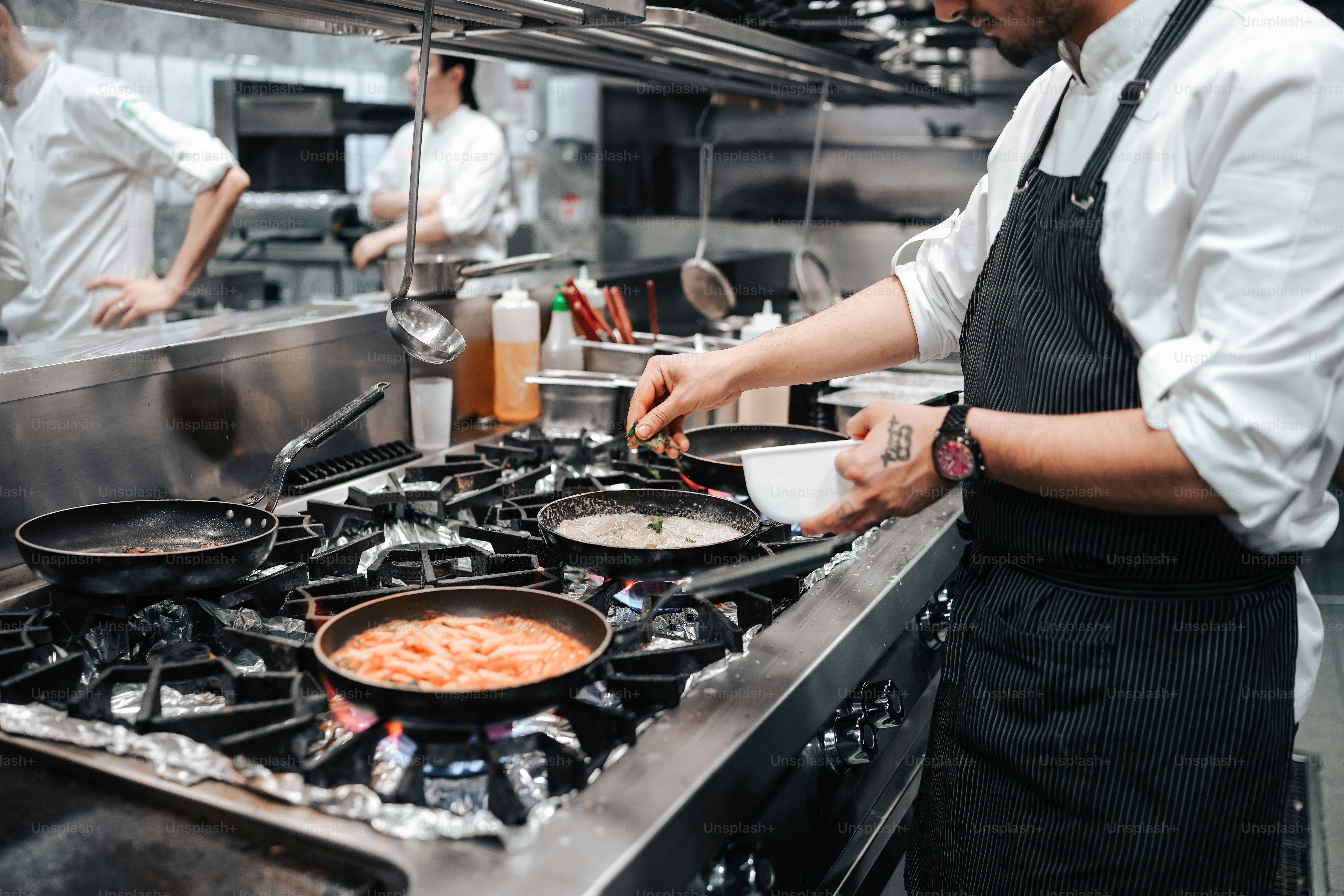 a man in a kitchen preparing food on top of a stove