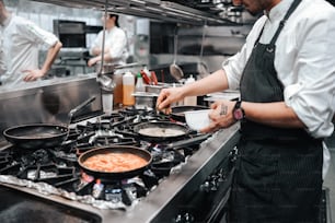 a man in a kitchen preparing food on top of a stove