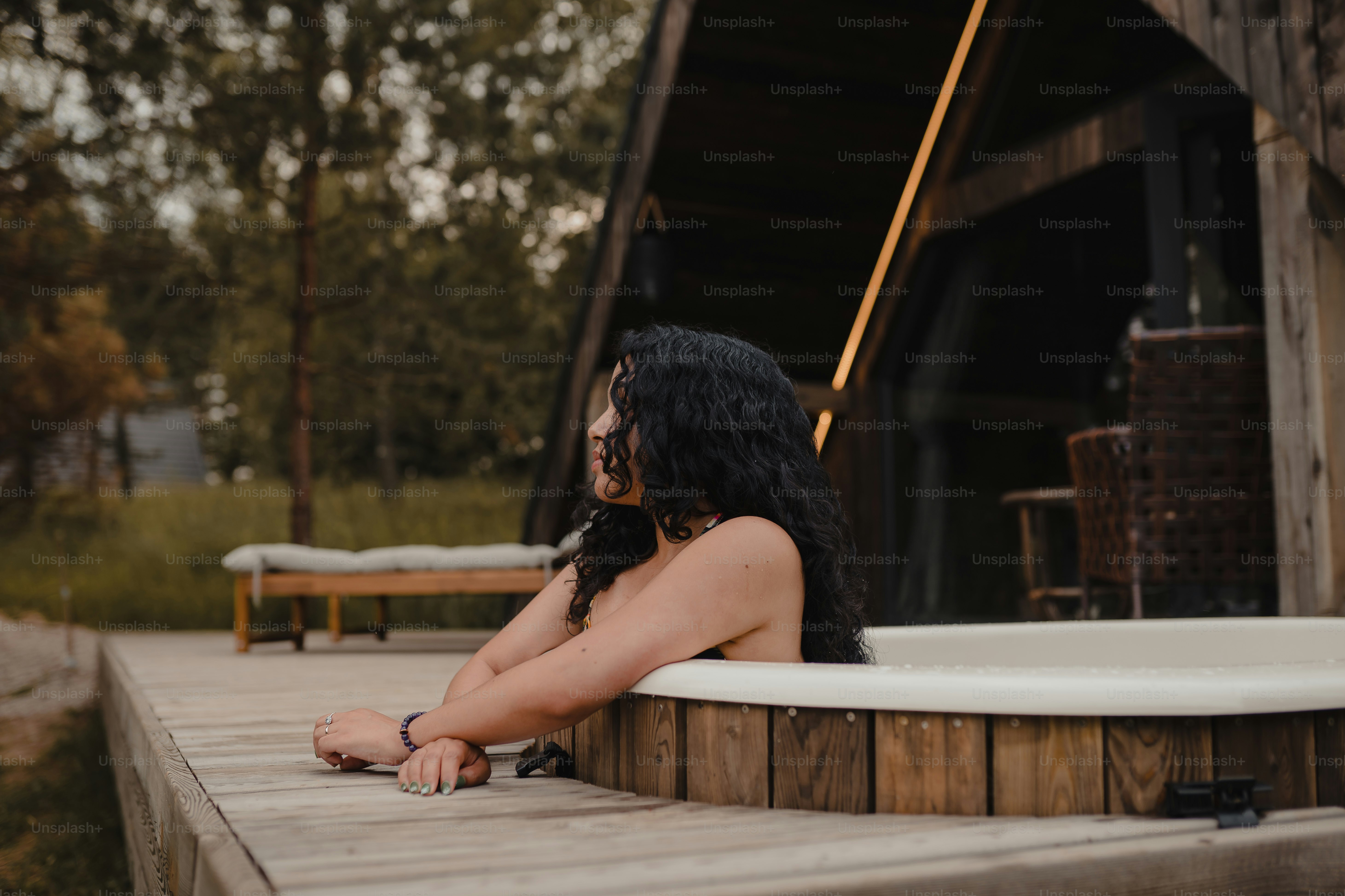 a woman sitting on a wooden deck next to a hot tub