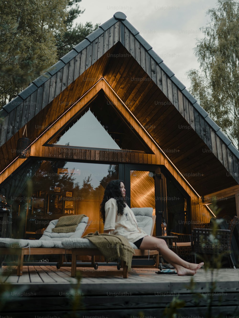una donna seduta su un ponte di fronte a una casa