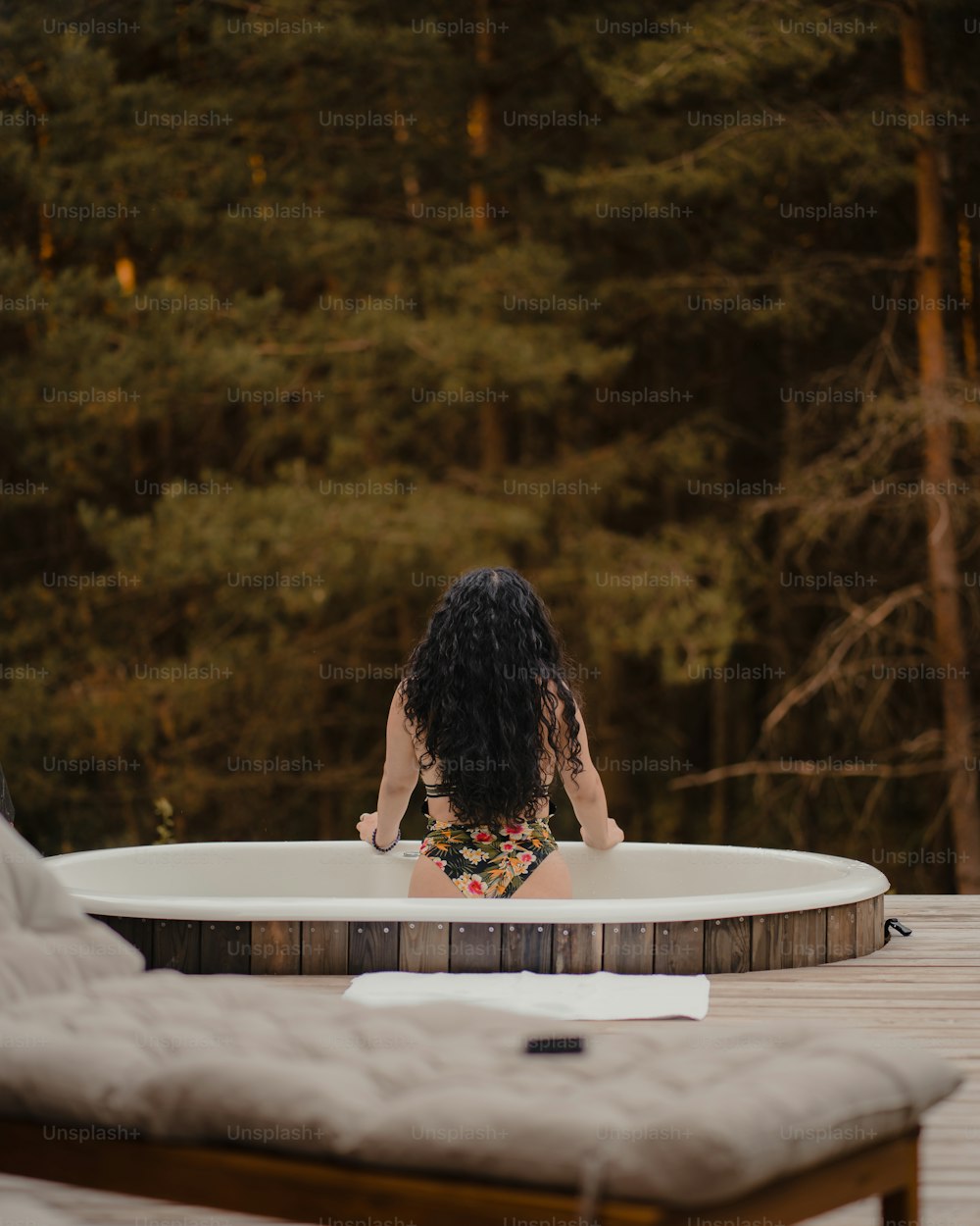 Una mujer sentada en una bañera de hidromasaje con árboles en el fondo