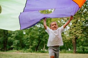 a young boy holding a kite in a field