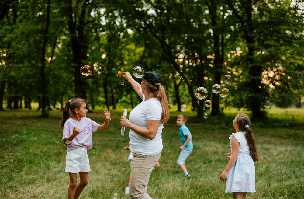 a group of children and a woman playing with soap bubbles