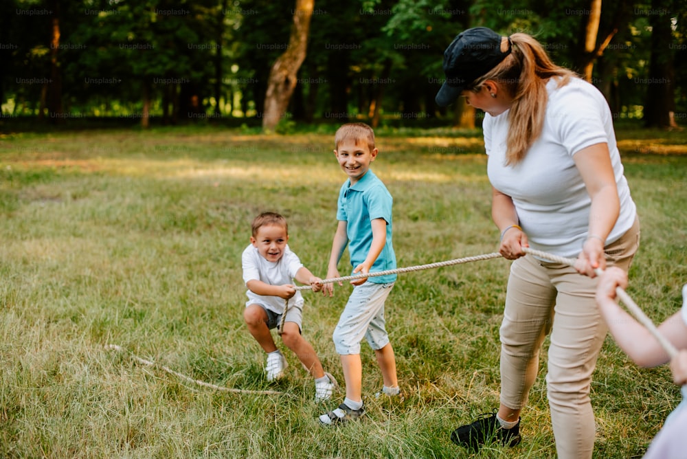 Una donna e due bambini che giocano a tiro alla fune in un campo