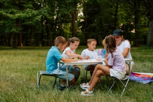 un gruppo di bambini seduti intorno a un tavolo nell'erba