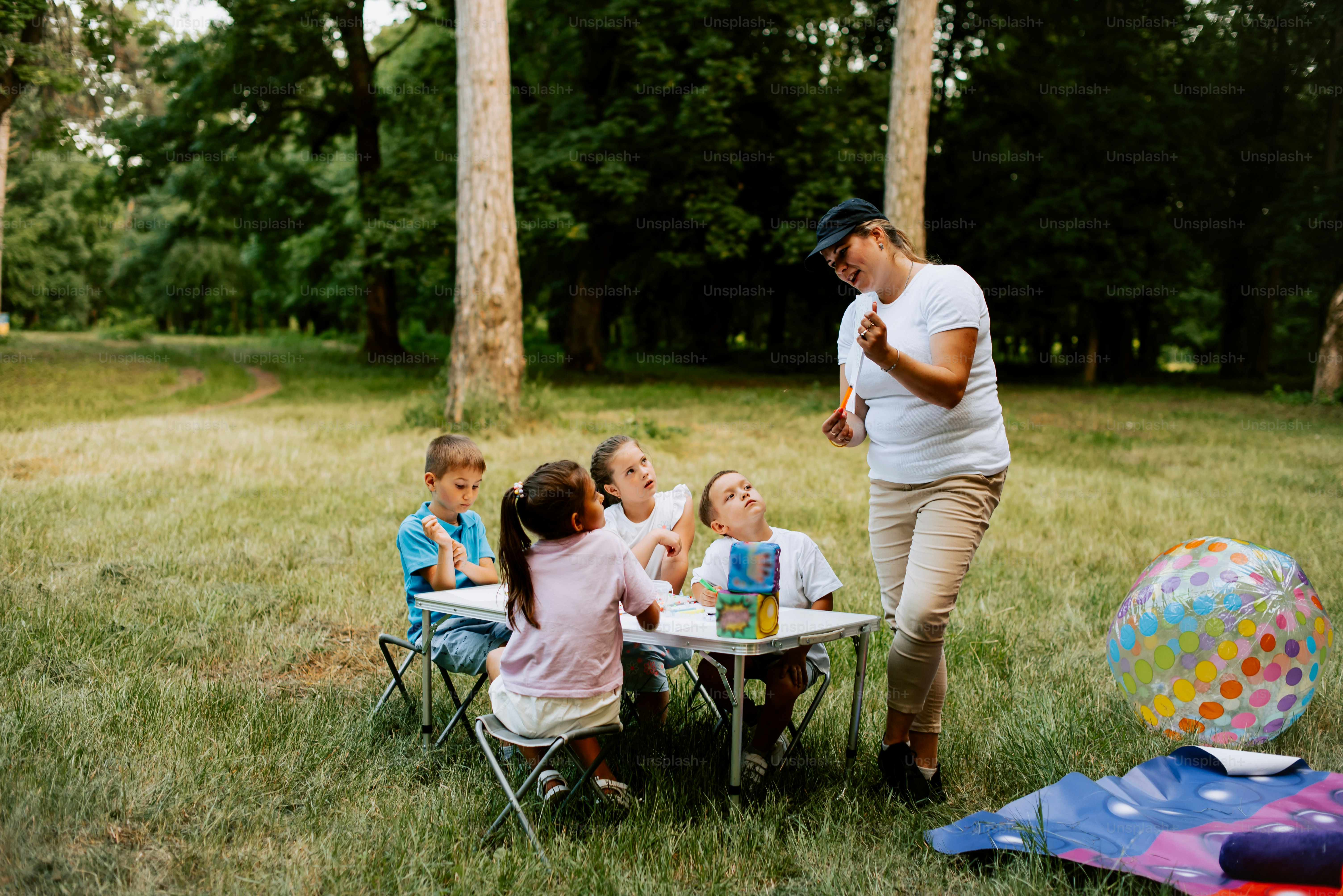 a woman standing in front of a group of children sitting at a table
