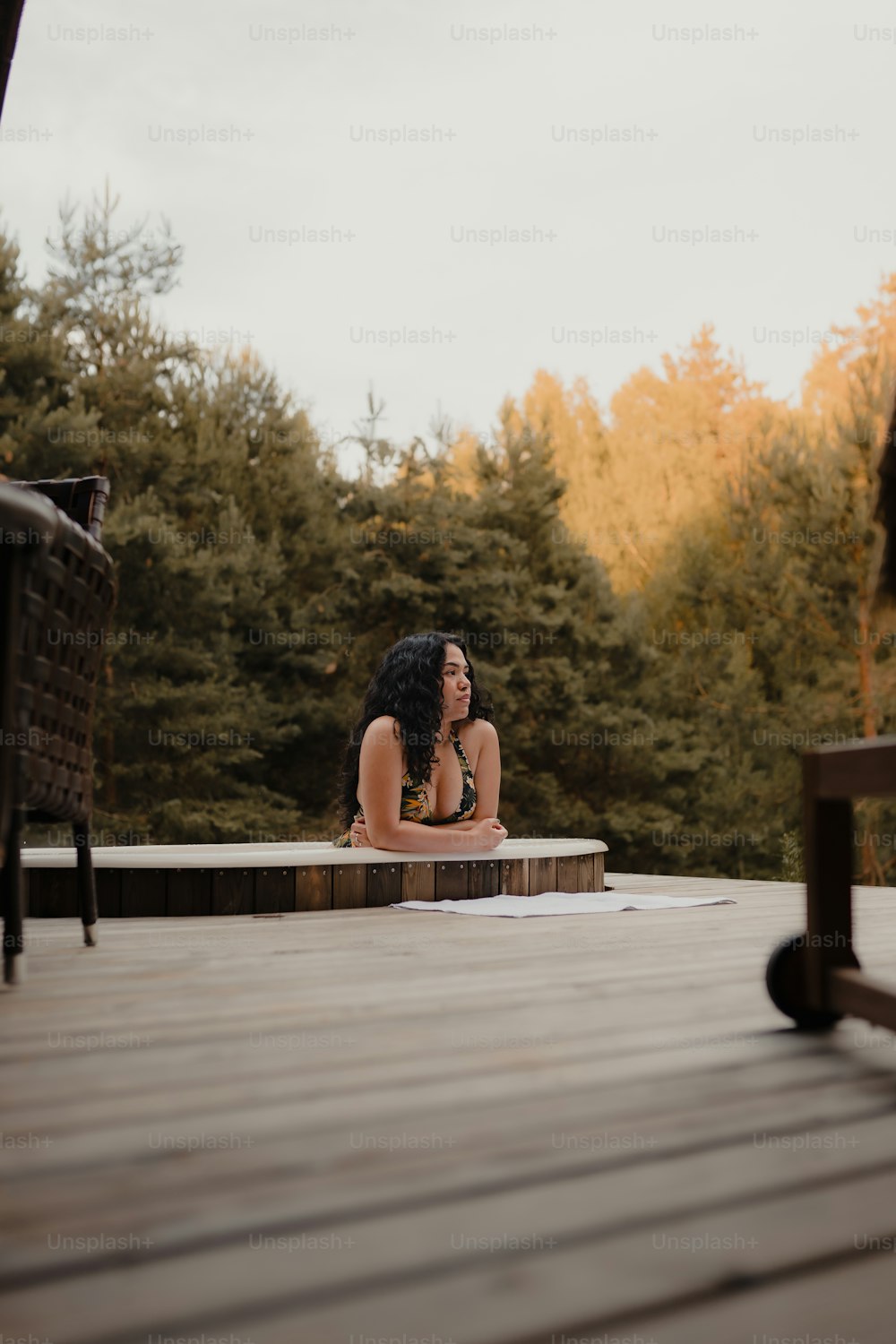 a woman is sitting on a wooden deck